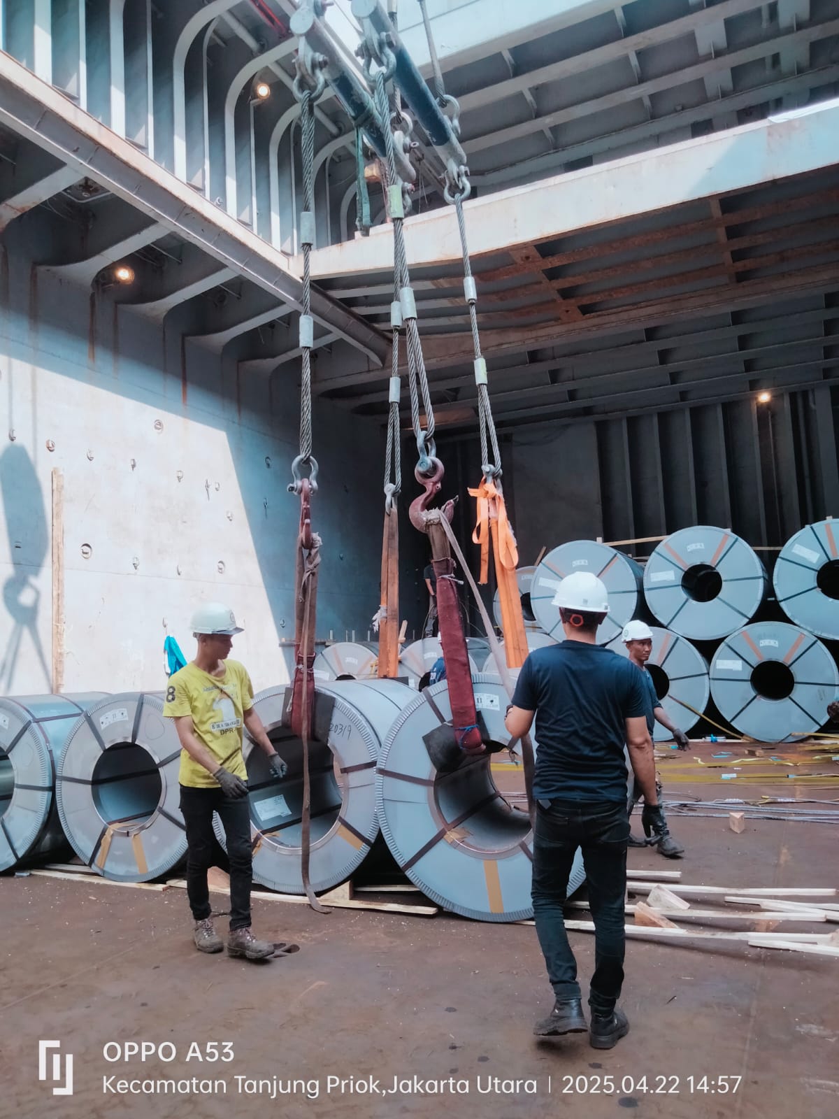Team coordination during lifting operation of steel coils at Tanjung Priok Port, emphasizing safety and teamwork